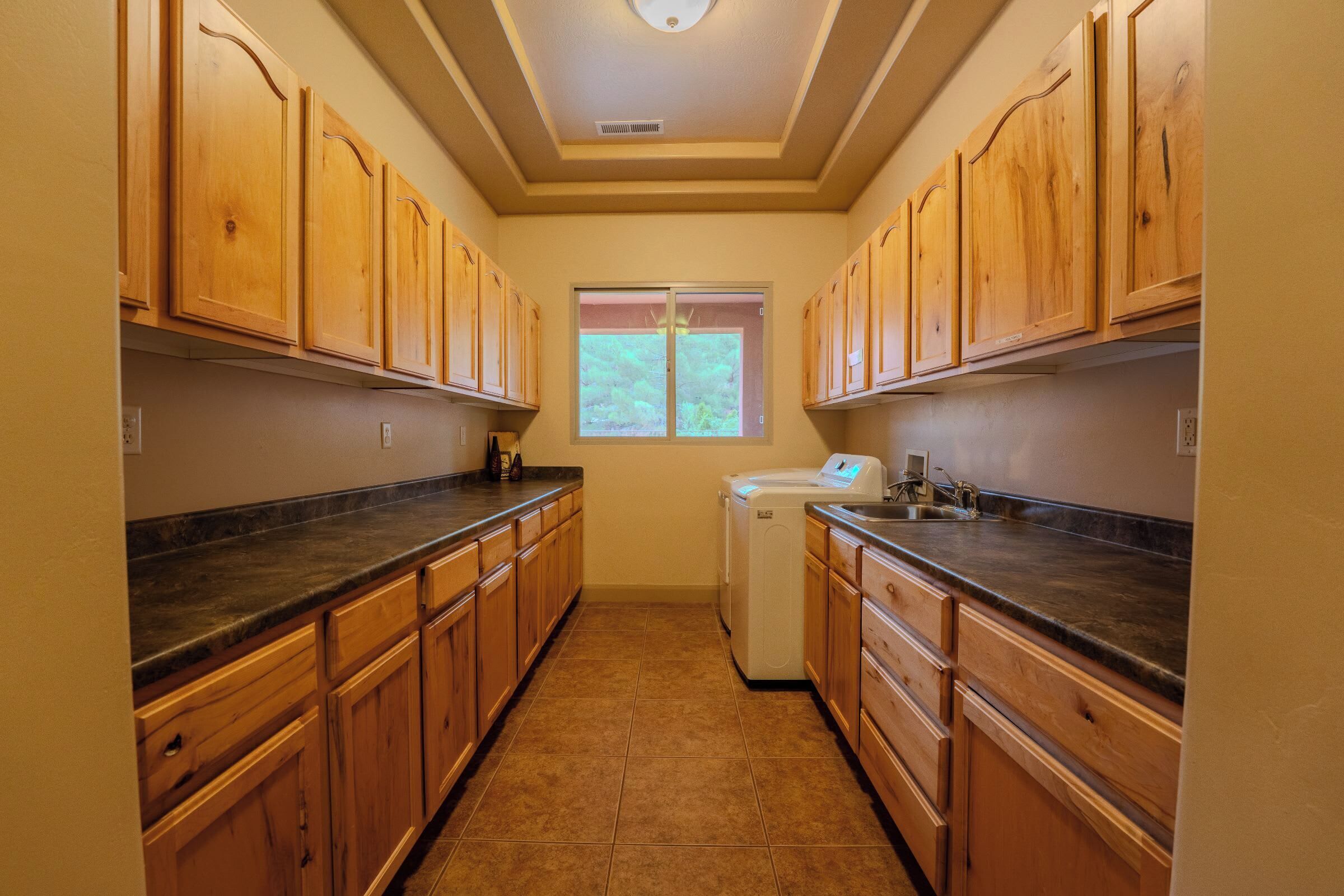A narrow kitchen with wooden cabinets and a built-in washer and dryer.