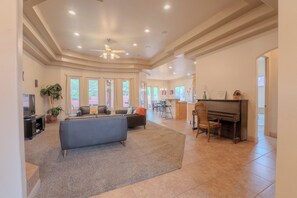A spacious living area with a sofa, a piano, and a television.