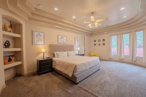 A bedroom with a large bed, a ceiling fan, and multiple windows. - Spirit of the Rock - Kanab home w/ pool & hot tub (Kanab)