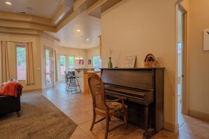 A living room with a piano, a chair, a rug, and a fireplace. - Spirit of the Rock - Kanab home w/ pool & hot tub (Kanab)