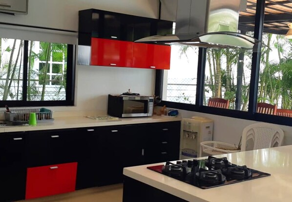 A modern kitchen with black and red cabinets, a microwave, and a gas stove.
