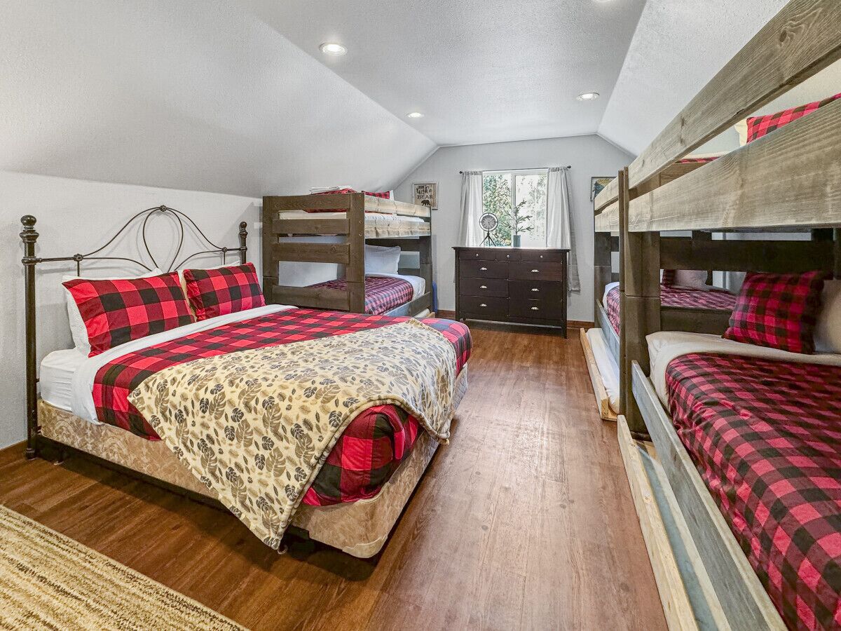 Un dormitorio con literas, un aparador y una ventana con cortinas.