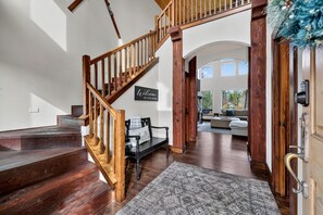 A wooden staircase leading to a living area with a bench, a rug, and a 'Welcome to our home' sign.
