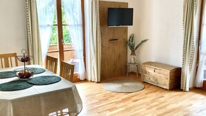 En matplats med ett bord dukat för fyra personer, en träbänk, en tv som är monterad på en träpanel och en liten trälåda.