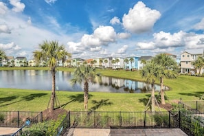 A residential area with a pond, palm trees, and houses with various roof colors.