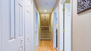 A hallway with white doors, a carpeted staircase, and a wall-mounted picture.