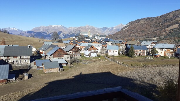 Ein Dorf mit traditionellen Holzhäusern, einer Kirche und Bergen im Hintergrund.