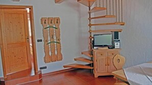 A room with a wooden door, a wall-mounted wooden shelf with a television, and a cabinet. - Vacation apartment 1, up to 5 persons, 65 sqm, 2 separate bedrooms (Schleching)