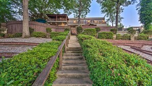 A stone staircase leading to a building with a wooden deck and a covered area. - Dock, Hot Tub & Kayaks: Luxe Hot Springs Lakehouse (Hot Springs)