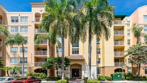A multi-story hotel with balconies, palm trees, and a clear blue sky. - Amazing view in Aventura! Cozy 2 BD at the Yacht Club (Aventura)