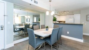 A modern kitchen with a central island, a dining area with a table and chairs, and a large mirror reflecting the space. - Amazing view in Aventura! Cozy 2 BD at the Yacht Club (Aventura)