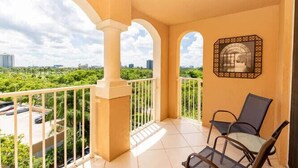 A balcony with a view of a cityscape, a chair, and a decorative wall piece. - Amazing view in Aventura! Cozy 2 BD at the Yacht Club (Aventura)