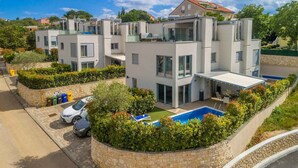 A modern residential building with a swimming pool, a covered outdoor area, and a stone retaining wall. - Villa with pool in the center of Malinska (Malinska)