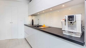 A modern kitchen with a built-in coffee machine, a sink, and a cutting board with a fruit. - Villa with pool in the center of Malinska (Malinska)