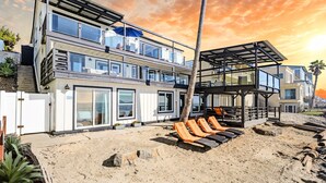 A modern multi-story beachfront property with a covered outdoor seating area and a view of the ocean. - Single Family Tranquil Beachfront Rental P1829-0 (Oceanside)