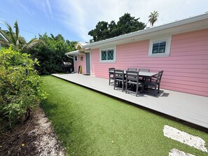 A pink house with a patio, a barbecue grill, and a table with chairs.
