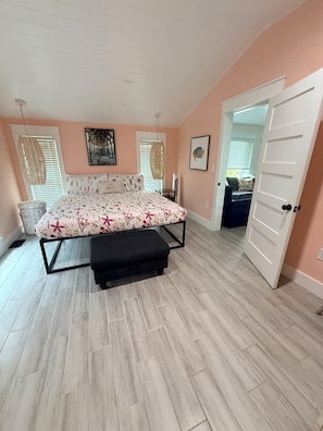 A bedroom with a bed, bench, and a door leading to another room. - WATER SLIDE & POOL ** SUGAR SHACK** (Bradenton)