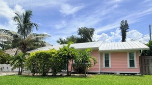 A pink house with a white roof, surrounded by a well-maintained lawn and palm trees. - WATER SLIDE & POOL ** SUGAR SHACK** (Bradenton)