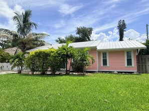 A pink house with a white roof, surrounded by a well-maintained lawn and palm trees. - WATER SLIDE & POOL ** SUGAR SHACK** (Bradenton)