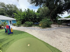 A backyard with artificial turf, a pool table, and a small palm tree.