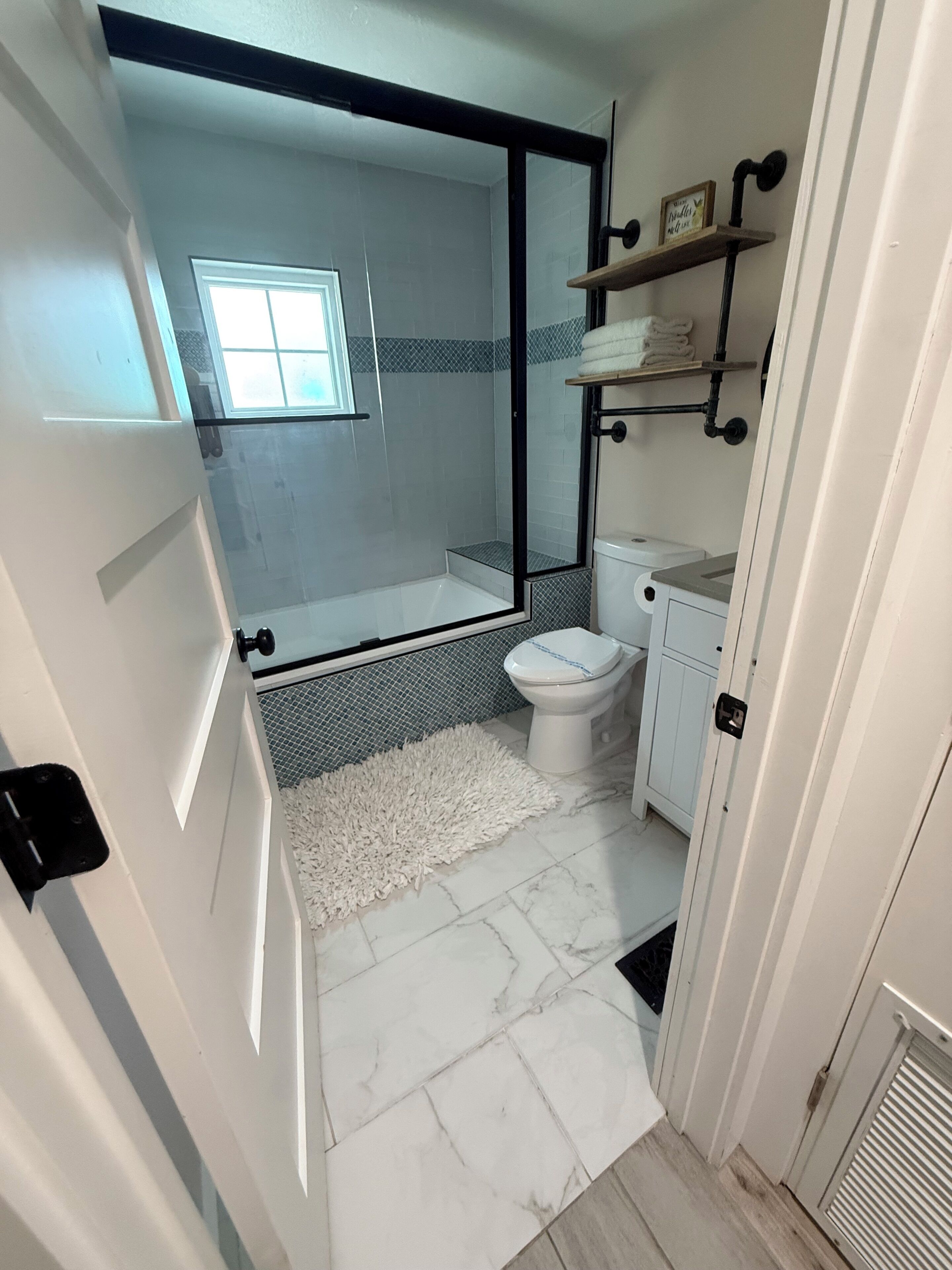 Un baño con cabina de ducha de vidrio, inodoro, lavamanos y espejo.