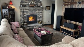 A cozy living room with a stone fireplace, a large flat-screen TV, and a comfortable sofa. - Private mountainside chalet bordering Dolly Sods with beautiful panoramic view. (Davis)