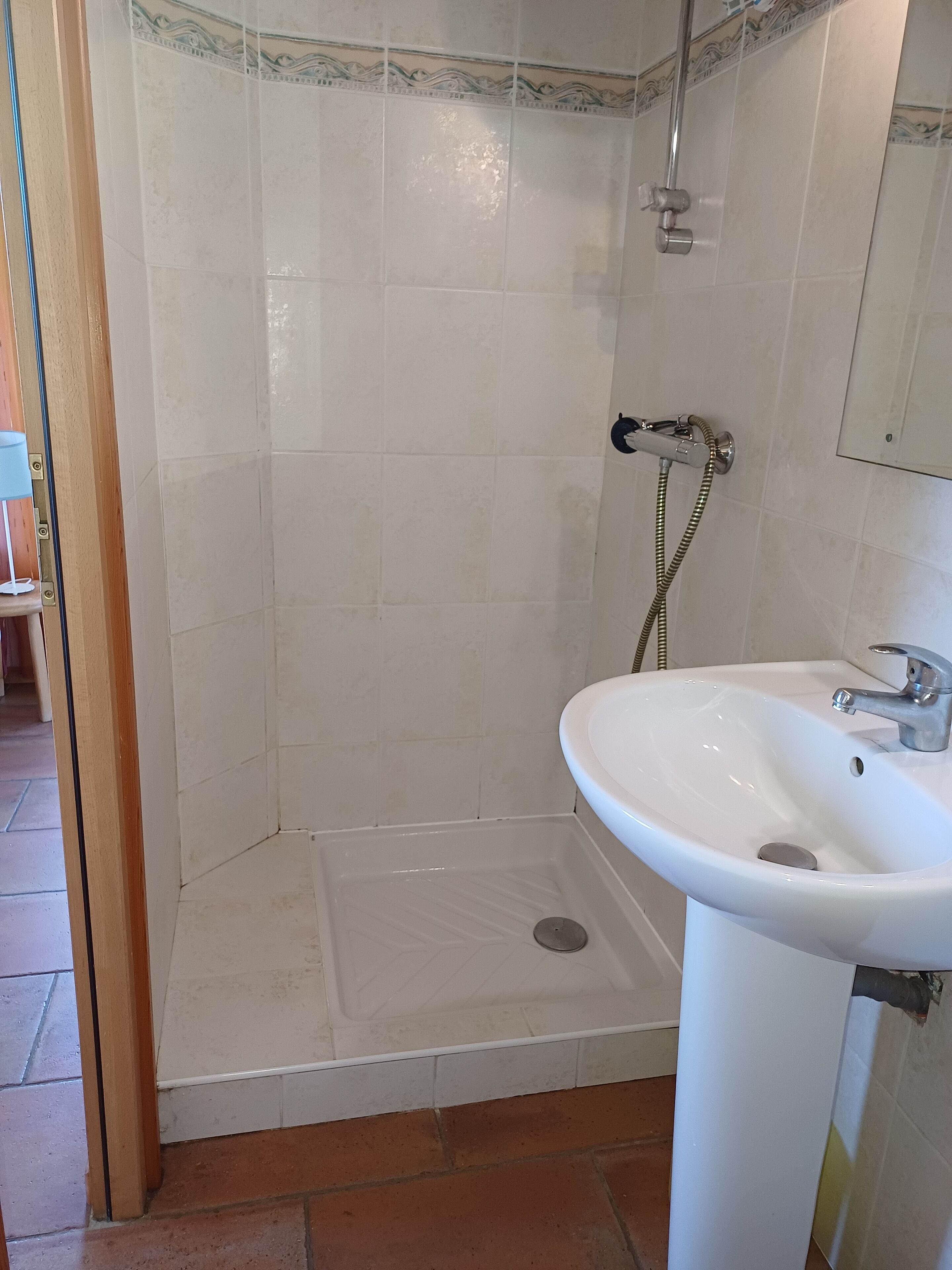 Ein Badezimmer mit Dusche, Waschbecken und Fliesenboden.