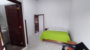 Une petite pièce propre, avec un lit, une table de chevet et une chaise.
