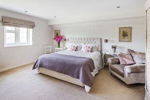 Relax in this serene bedroom with a large bed, tufted headboard, and plush armchair.