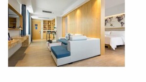 A modern hotel room with a sofa bed, a desk, and a bookshelf. - Kyriad Marvelous Hotel (Dongguan)