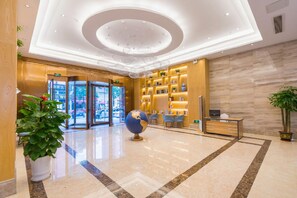 Un vestíbulo de hotel con mostrador de recepción, zona de estar y una escultura de un globo terráqueo.