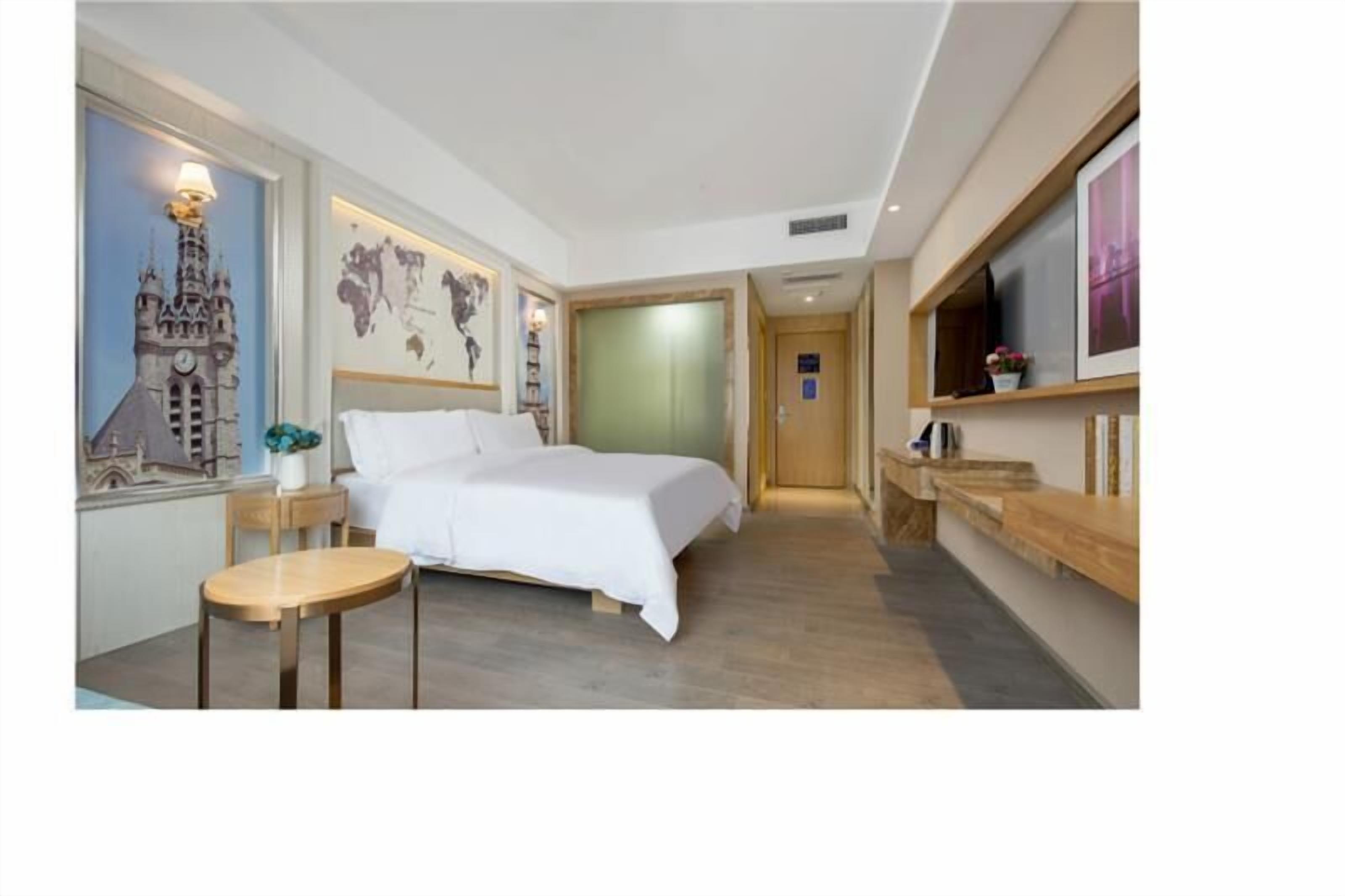 A hotel room with a bed, a small table, a TV, and a map on the wall.