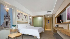 A hotel room with a bed, a small table, a world map on the wall, and a television on the right. - Kyriad Marvelous Hotel (Dongguan)