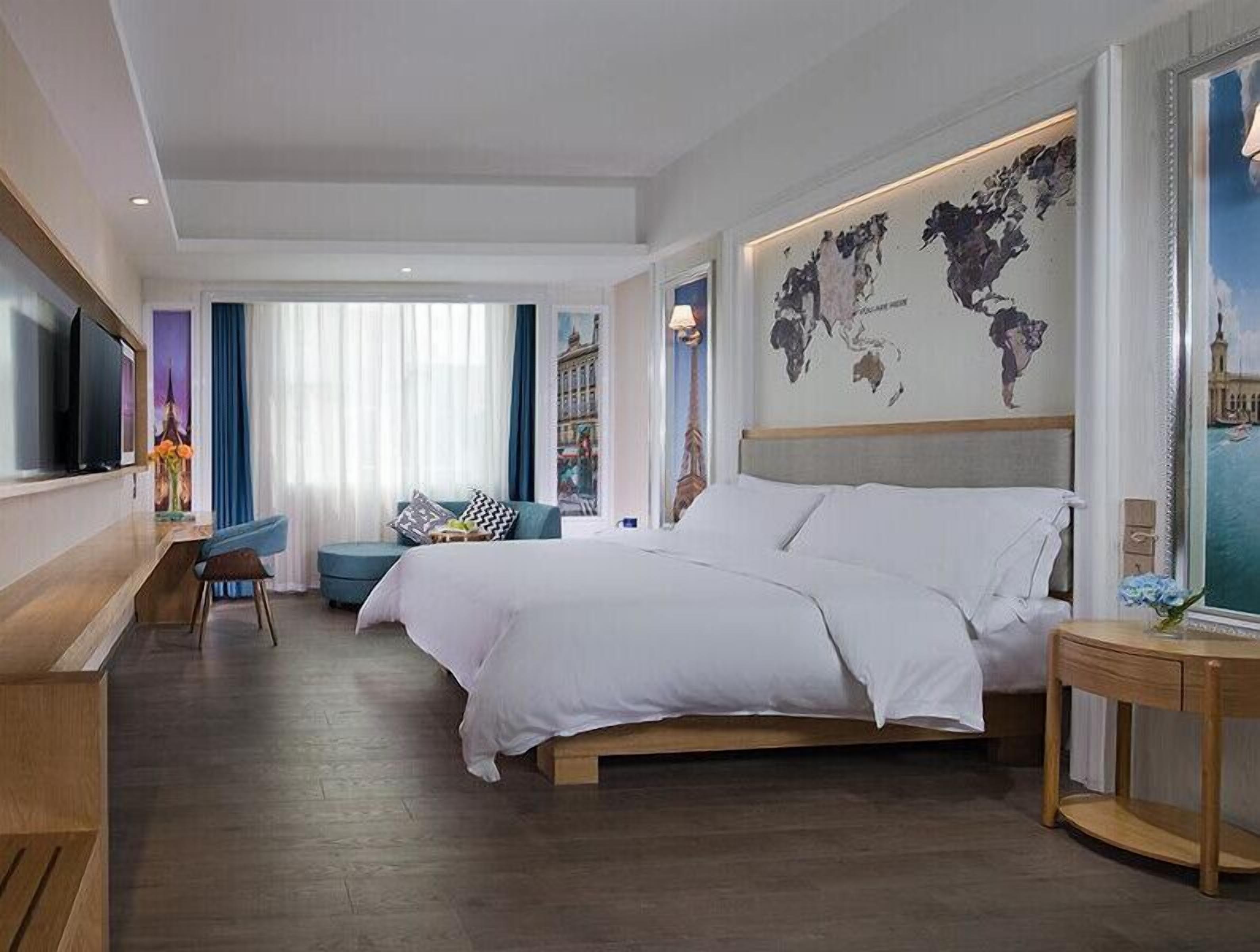 Een moderne hotelkamer met een groot bed, een bureau, een televisie en een wereldkaart aan de muur.
