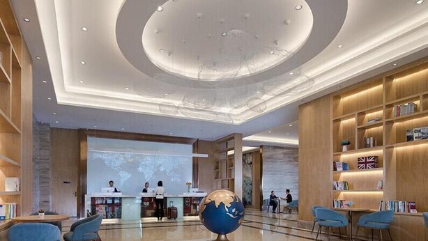 A spacious lobby with a reception desk, seating area, and a large globe sculpture. - Kyriad Marvelous Hotel (Dongguan)