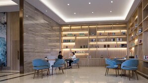 A modern lobby with a central seating area, a bookcase, and a marble floor. - Kyriad Marvelous Hotel (Dongguan)