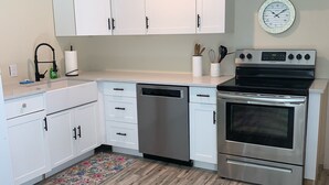 Een moderne keuken met witte kastjes, roestvrijstalen apparatuur en een houten vloer.