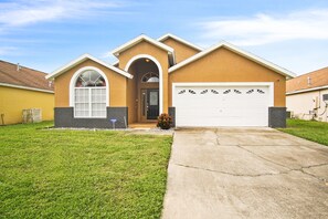 A single-story house with a garage, a front entrance with an archway, and a well-maintained lawn.