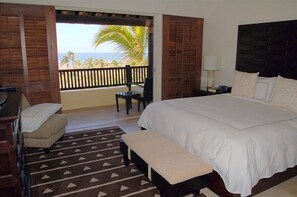 Relax in this serene retreat with a large bed, ocean views, and a balcony overlooking palm trees.