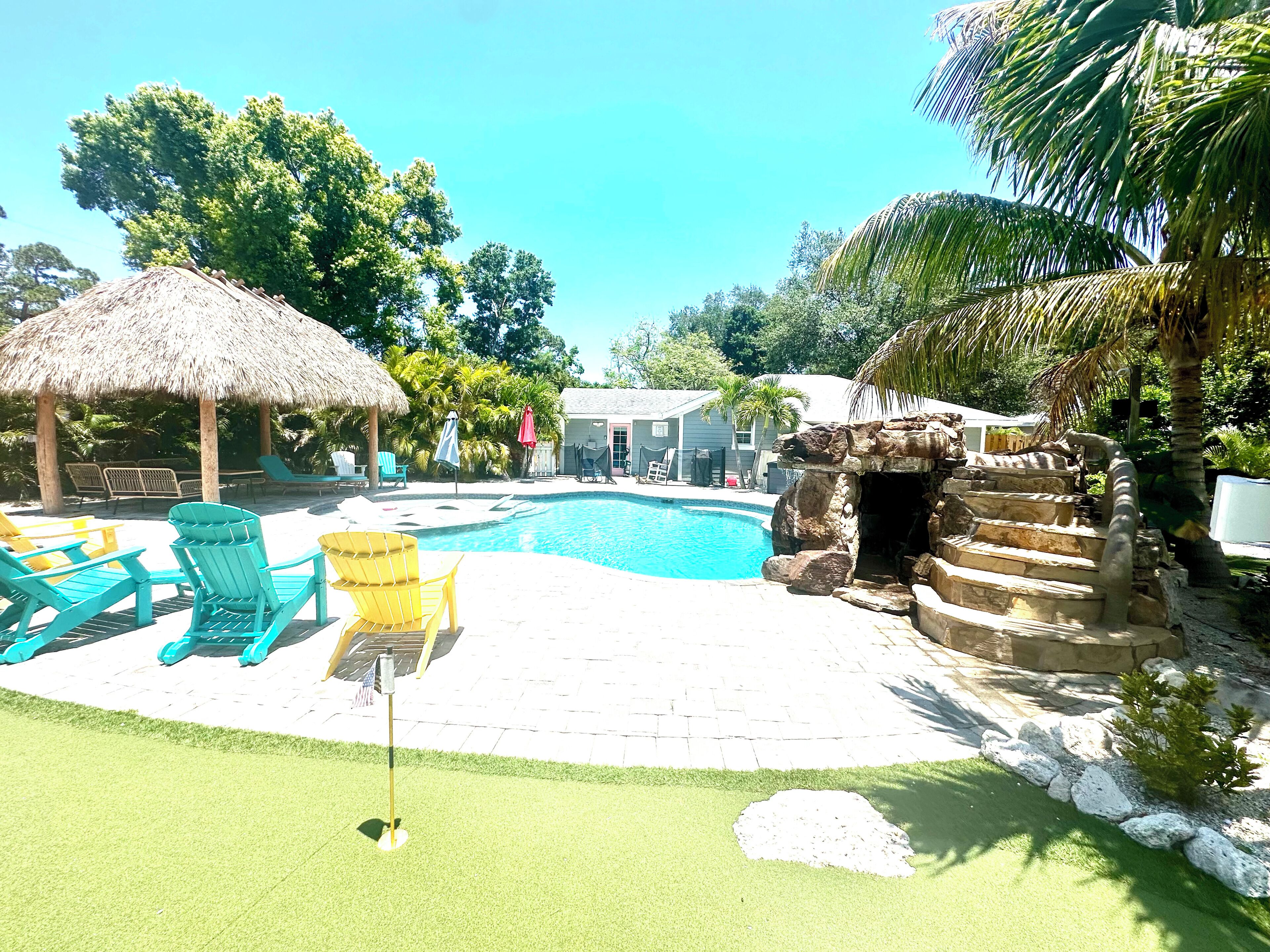 A swimming pool with lounge chairs and a thatched-roof structure.