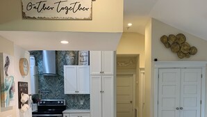 A kitchen with a central island, white cabinets, and a 'Gather Together' sign. - WATER SLIDE & POOL ** Sugarcane Hideaway** (Bradenton)