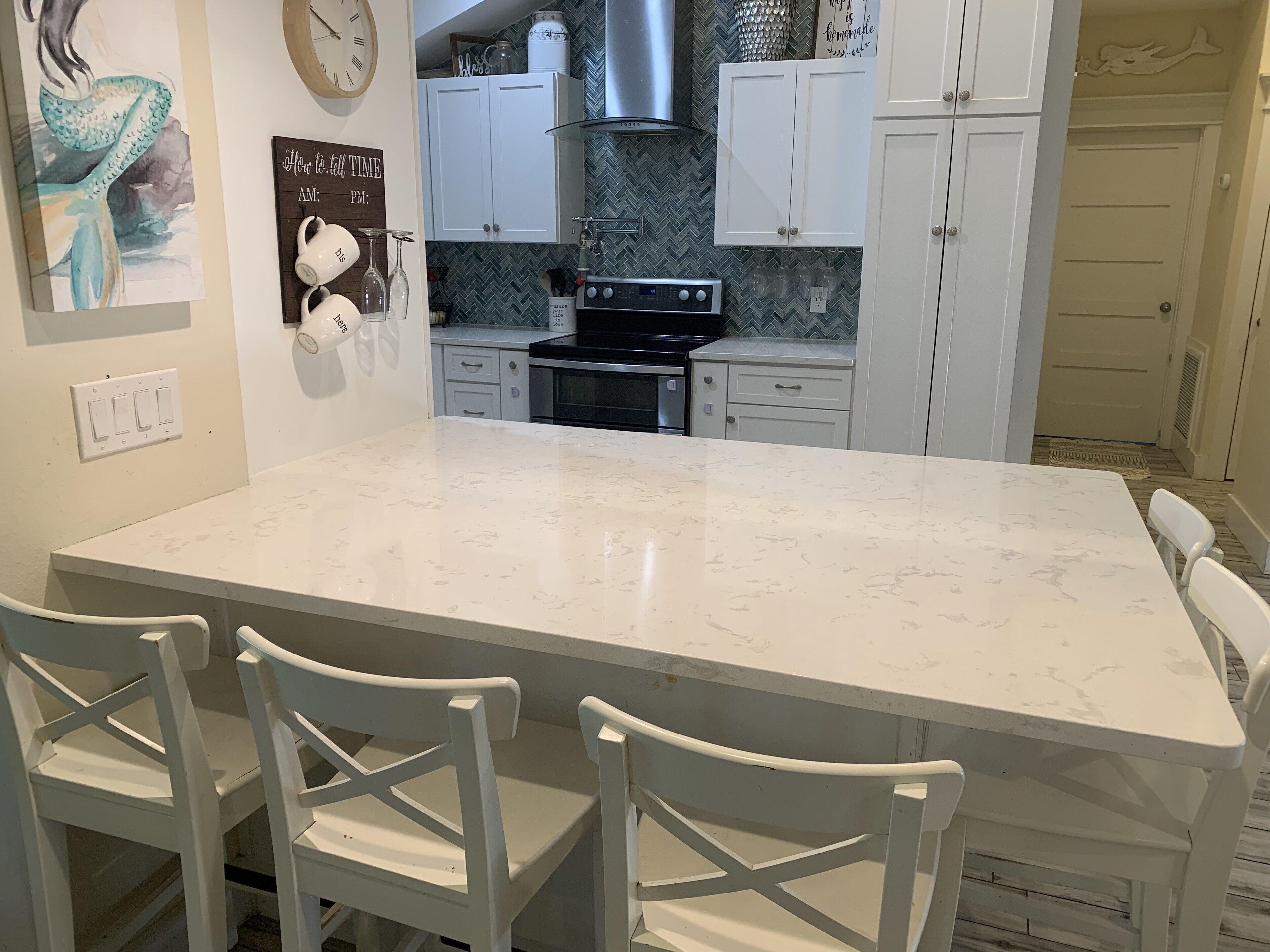 A kitchen with a large island, white cabinetry, and a clock on the wall.