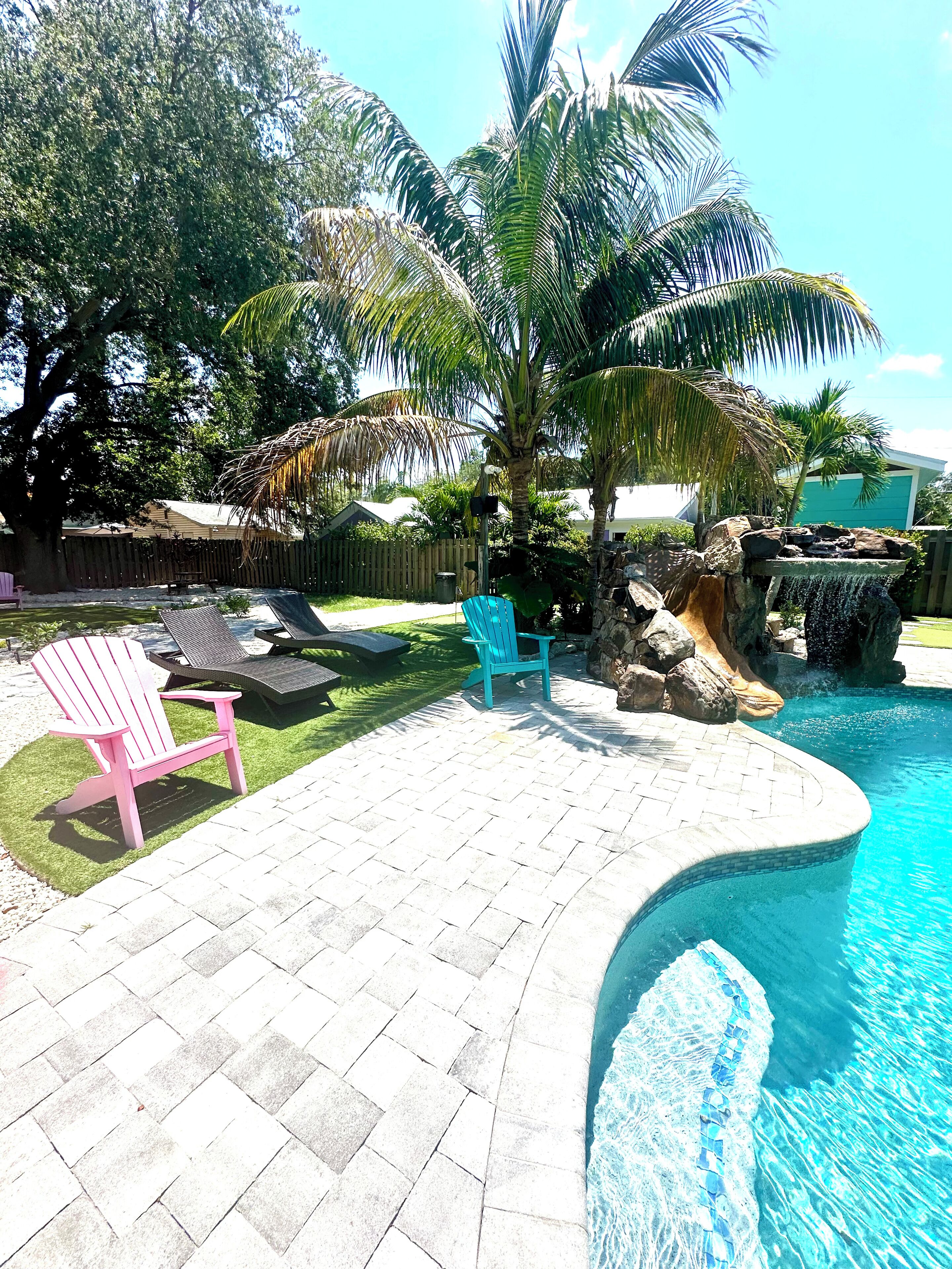 Ein Garten mit Swimmingpool, einer Holzterrasse und einem kleinen Wasserfall.