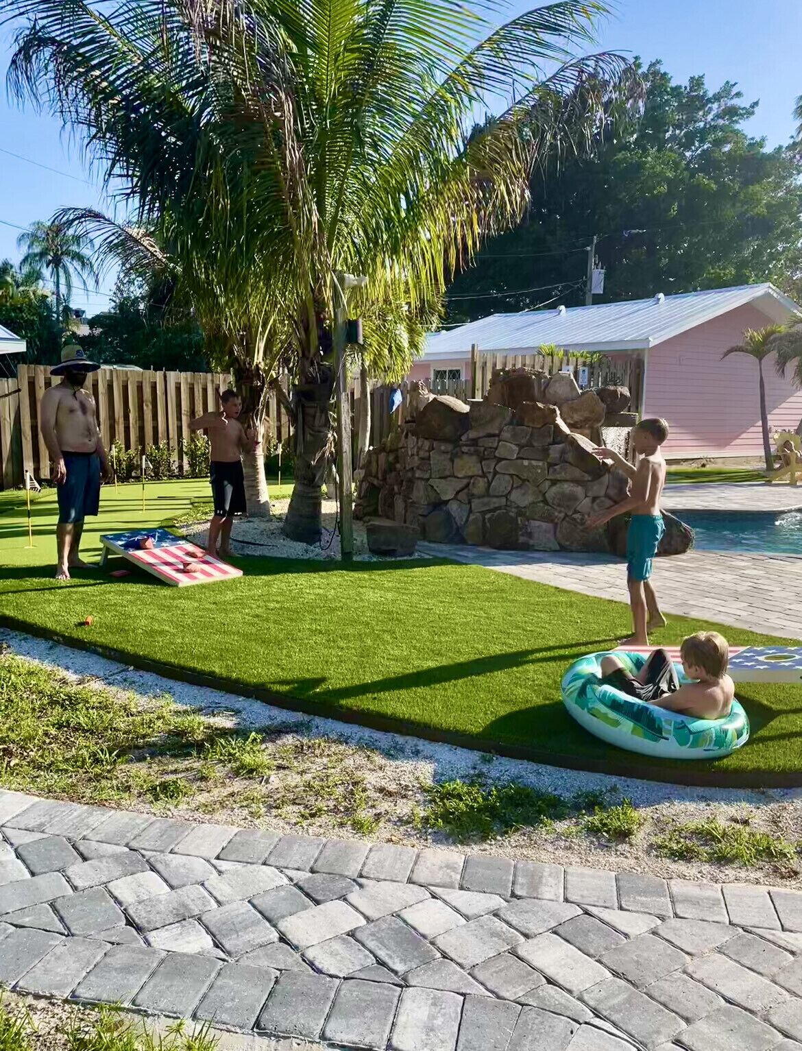 Um quintal com muro de pedra, palmeira e piscina.