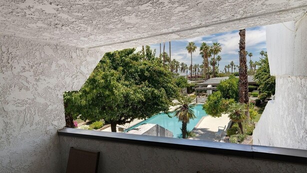 A view from a balcony with a pool and palm trees. - Paradise in Palm Springs, Cozy Condo 2BDR/2BA + Den, Balcony with Pool View (Palm Springs)