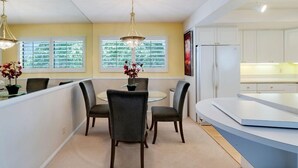 A modern kitchen with white cabinets, a white refrigerator, and a dining area with a round table and four chairs. - Paradise in Palm Springs, Cozy Condo 2BDR/2BA + Den, Balcony with Pool View (Palm Springs)