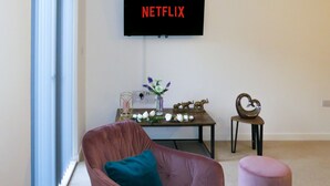 A living room with a flat-screen TV mounted on the wall displaying "NETFLIX".