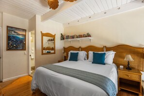 Una camera da letto con un letto grande, un comodino, una mensola, uno specchio, una libreria e un quadro appeso al muro.