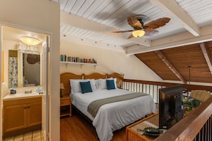 A bedroom with a bed, bedside table, TV, and a ceiling fan.