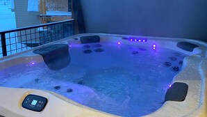 A hot tub with a control panel, surrounded by a wooden deck and a stone wall. - BRAND NEW Contemporary 2 BR near Winter Park Ski Resort on Shuttle w/priv hottub (fraser)